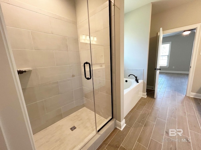 full bath with baseboards, a shower stall, a bath, and wood tiled floor