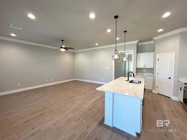 kitchen with visible vents, a center island with sink, a sink, wood finished floors, and white cabinetry