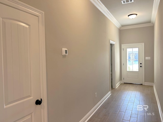 doorway to outside with crown molding, wood finished floors, baseboards, and visible vents