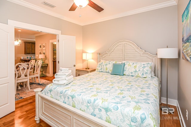 bedroom featuring light wood-style flooring, a ceiling fan, visible vents, baseboards, and ornamental molding