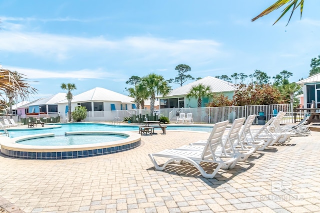 community pool with fence, a hot tub, and a patio