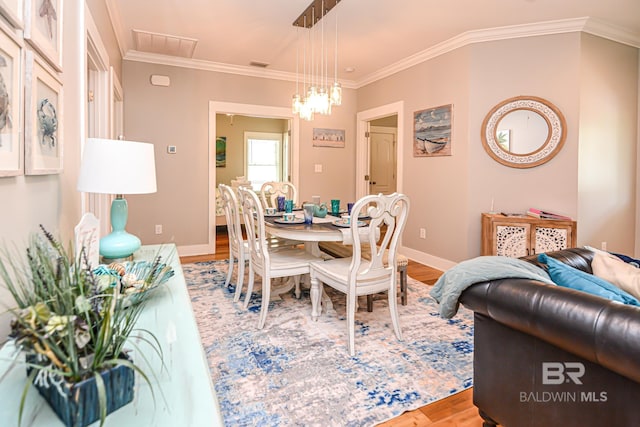 dining area featuring visible vents, crown molding, baseboards, and wood finished floors