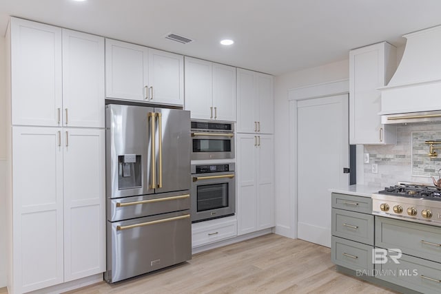 kitchen featuring appliances with stainless steel finishes, custom exhaust hood, backsplash, white cabinetry, and recessed lighting