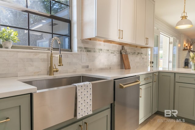 kitchen with stainless steel dishwasher, decorative backsplash, light countertops, and healthy amount of natural light