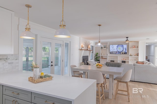kitchen with gray cabinets, light wood-style flooring, open floor plan, and hanging light fixtures