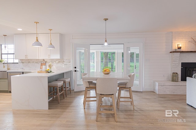 dining area featuring light wood-style flooring, a brick fireplace, and recessed lighting