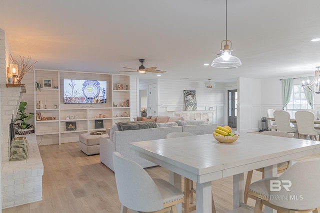 dining space featuring a chandelier, light wood-type flooring, ceiling fan, recessed lighting, and a brick fireplace