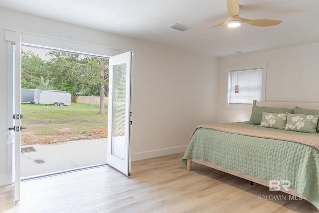 bedroom featuring multiple windows, wood finished floors, access to outside, and baseboards
