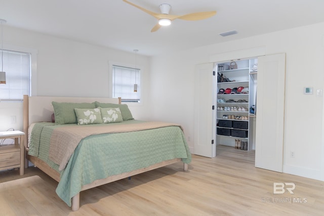 bedroom featuring light wood-type flooring, a spacious closet, a closet, and a ceiling fan