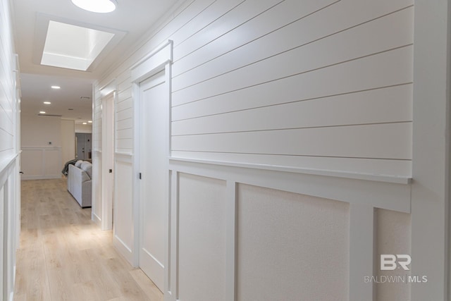 hallway featuring light wood-style floors, a decorative wall, and recessed lighting