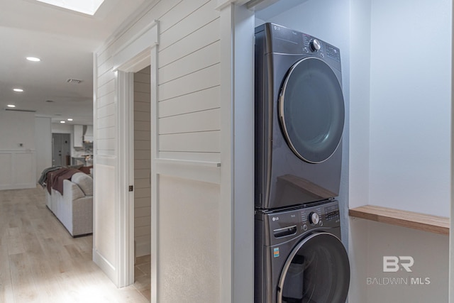laundry room featuring stacked washing machine and dryer, wood finished floors, and recessed lighting