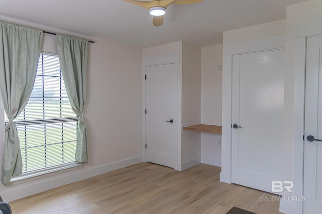 unfurnished bedroom featuring light wood-type flooring, baseboards, and ceiling fan