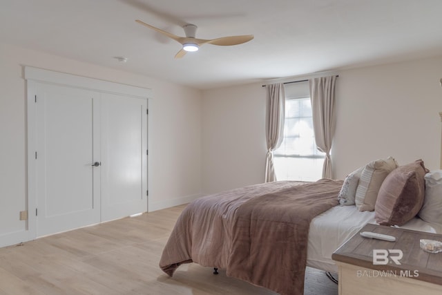bedroom with light wood finished floors, baseboards, and a ceiling fan