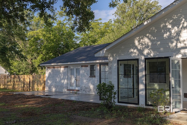 rear view of property featuring fence, a patio, and brick siding