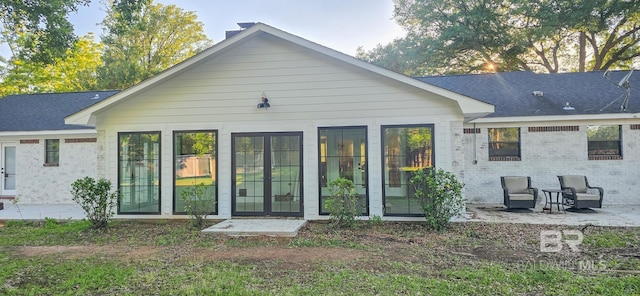 back of house featuring brick siding, a patio, and roof with shingles