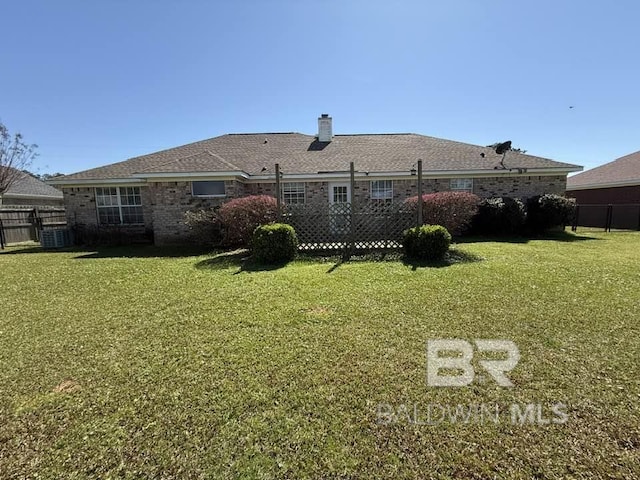 rear view of house with a yard, fence, brick siding, and a chimney