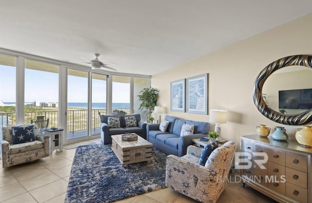 living room with a water view, ceiling fan, light tile patterned flooring, and floor to ceiling windows