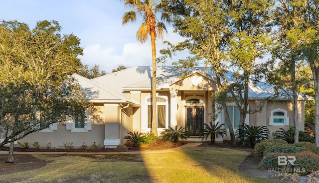 view of front of home featuring a front yard, metal roof, and stucco siding