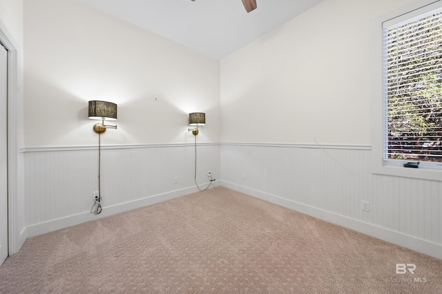 spare room featuring carpet floors, a wainscoted wall, and a ceiling fan