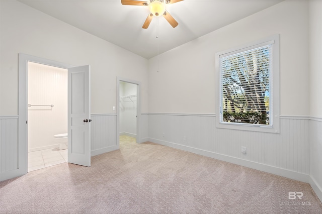 unfurnished bedroom featuring wainscoting, carpet flooring, connected bathroom, and a spacious closet