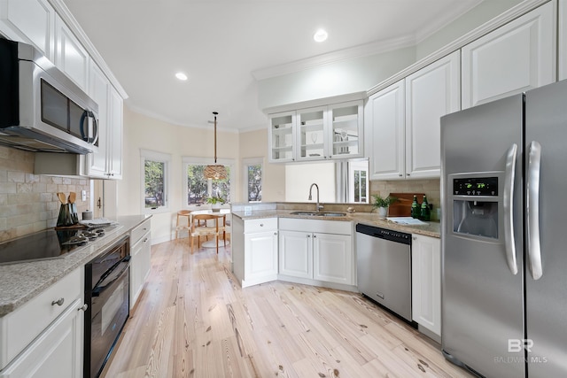 kitchen with a peninsula, crown molding, black appliances, white cabinetry, and a sink