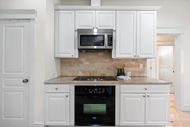 kitchen featuring black appliances, white cabinets, and backsplash