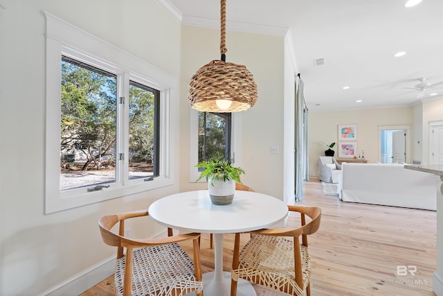 dining room featuring light wood-type flooring, visible vents, baseboards, and crown molding