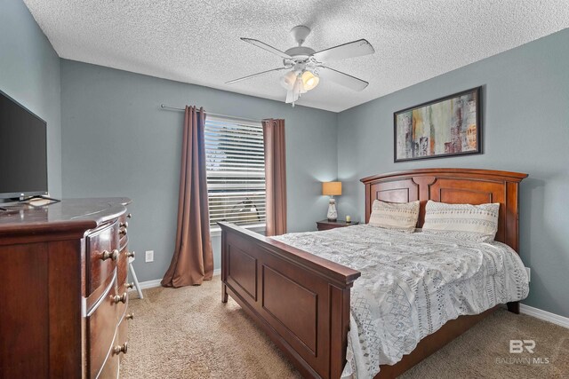 bedroom with light colored carpet, a textured ceiling, baseboards, and ceiling fan