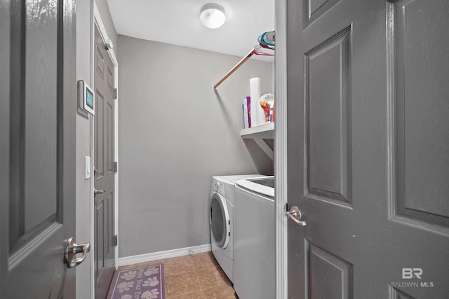 laundry area with laundry area, washing machine and dryer, and baseboards