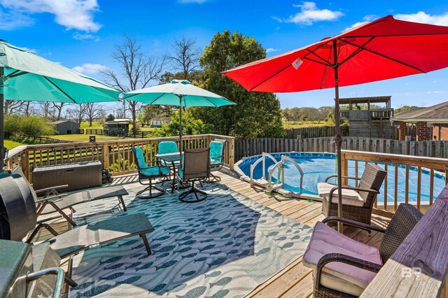 wooden terrace featuring outdoor dining space, a fenced in pool, and a fenced backyard