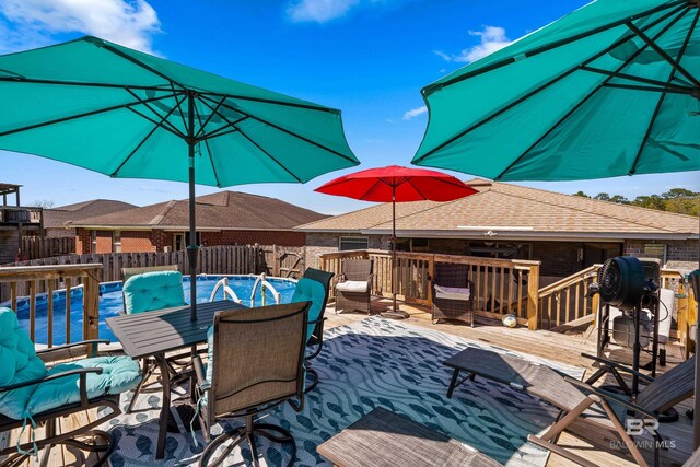 view of pool featuring outdoor dining area, fence, a fenced in pool, and a wooden deck