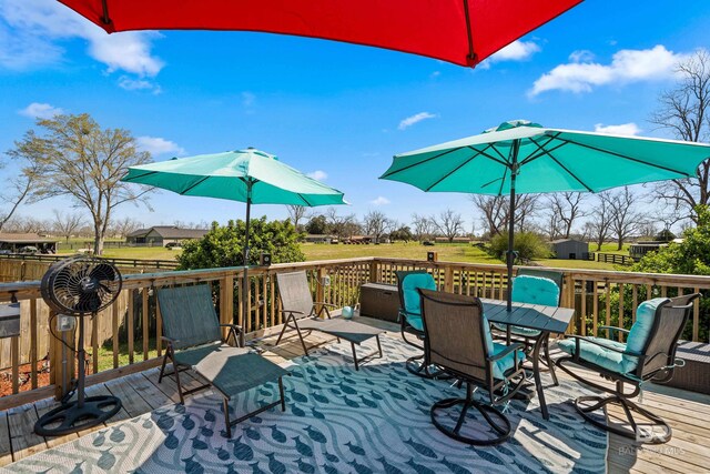 deck featuring a storage unit, a yard, an outbuilding, and outdoor dining space