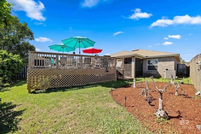 rear view of property featuring a lawn, brick siding, a fenced backyard, and a wooden deck