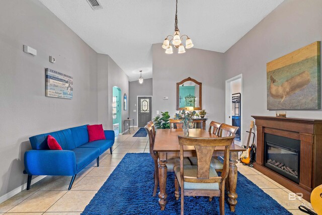 dining area with a glass covered fireplace, an inviting chandelier, light tile patterned flooring, and baseboards