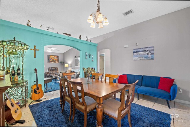 dining room with light tile patterned floors, visible vents, arched walkways, and a textured ceiling