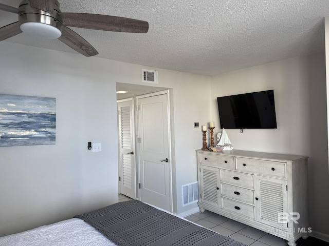 bedroom featuring visible vents, a textured ceiling, ceiling fan, and tile patterned flooring