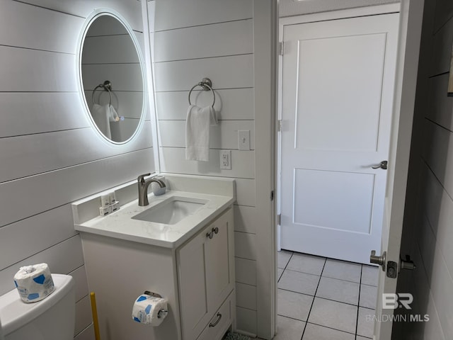 half bath featuring vanity, tile walls, toilet, and tile patterned flooring