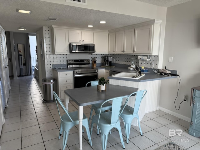 kitchen featuring visible vents, a sink, a textured ceiling, stainless steel appliances, and light tile patterned floors