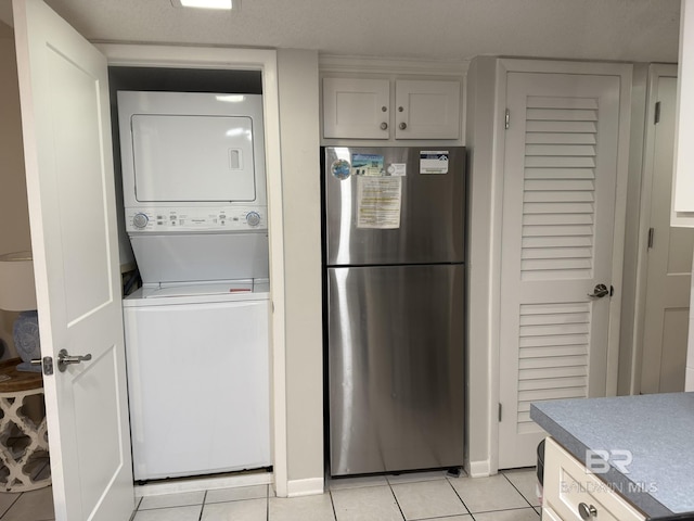 laundry room with light tile patterned flooring, laundry area, and stacked washer / dryer