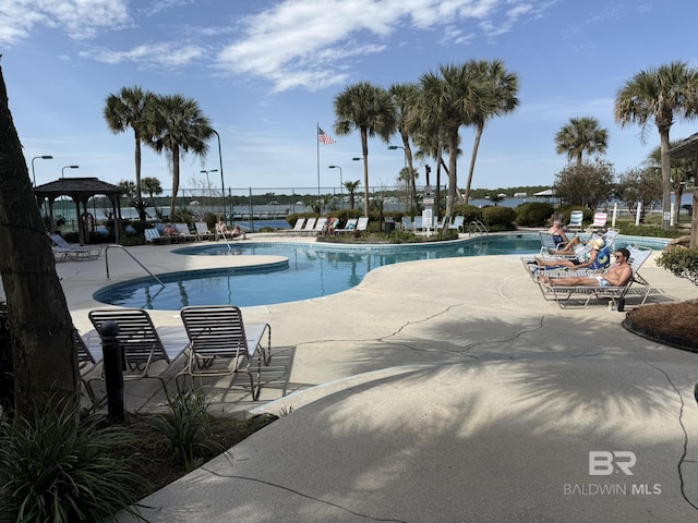 community pool with a gazebo, fence, and a patio area