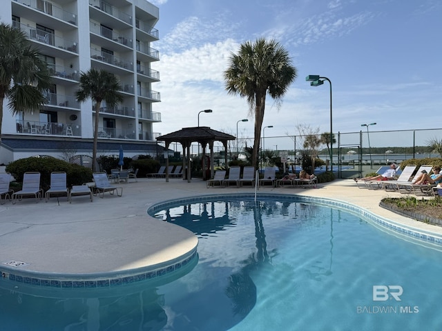 pool with a patio area and fence