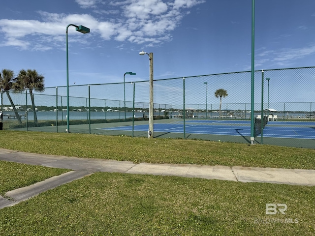 view of tennis court featuring a yard and fence