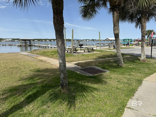 view of property's community featuring a water view, a lawn, and a boat dock