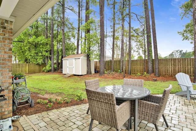 view of patio with a storage unit, a fenced backyard, an outdoor structure, and outdoor dining space
