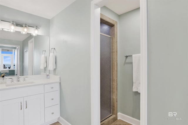 full bath with a stall shower, vanity, and baseboards