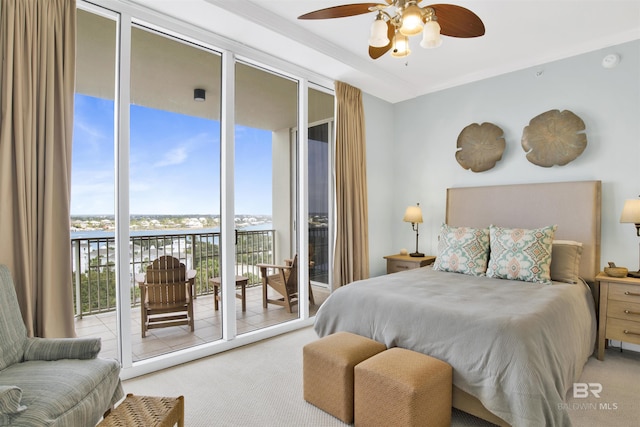 bedroom with access to exterior, light colored carpet, a water view, and a wall of windows