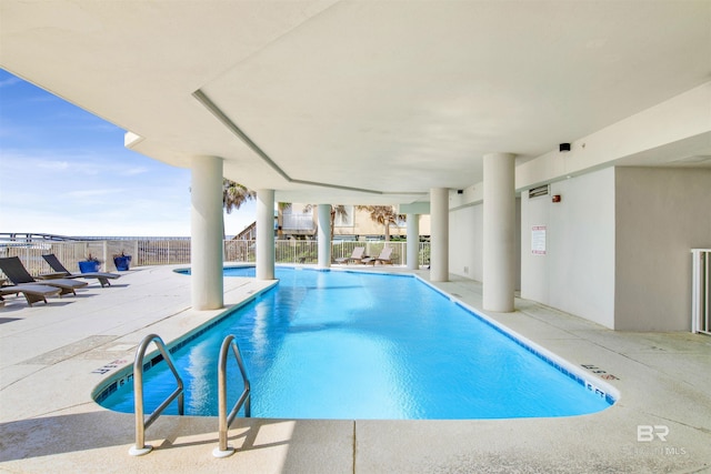 community pool with a patio area and fence