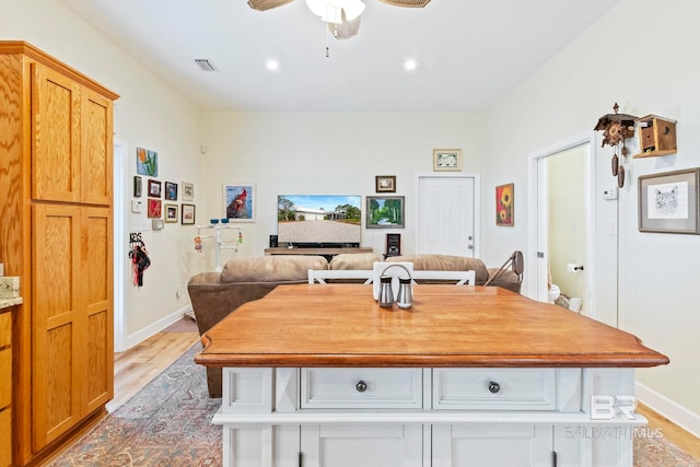 kitchen with light countertops, visible vents, light wood-style flooring, a ceiling fan, and baseboards