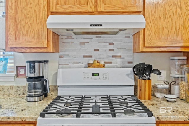 kitchen featuring gas range gas stove, exhaust hood, and light stone countertops