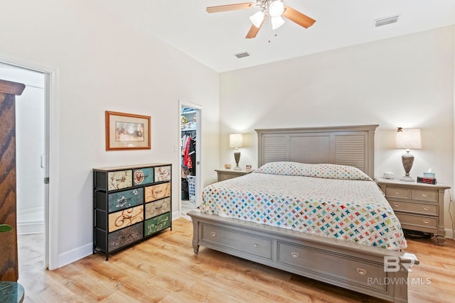 bedroom featuring baseboards, visible vents, light wood-style flooring, a spacious closet, and a closet